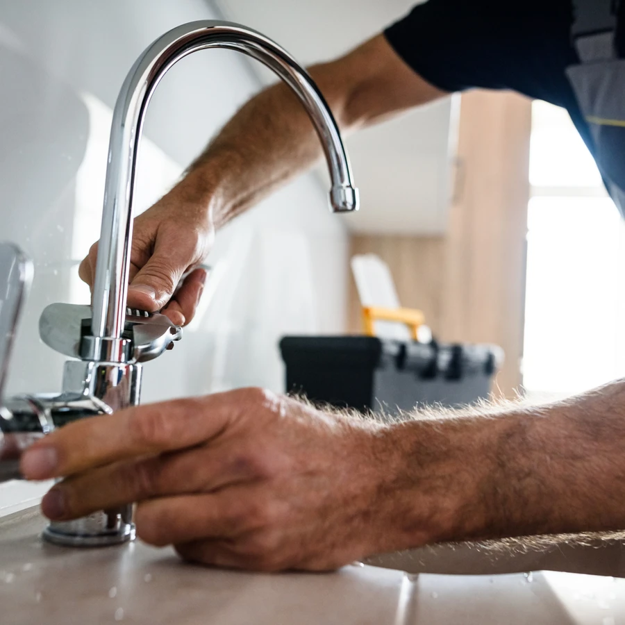 Plombier installant un robinet mitigeur chromé moderne sur un plan de travail blanc