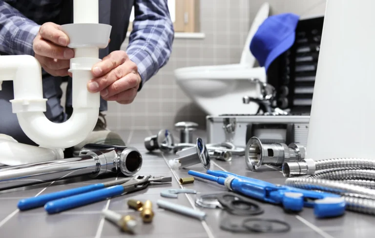 Plombier installant un siphon sous lavabo avec outils et accessoires de plomberie